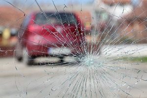 Broken windshield with red car in background | Could Your Car Accident Cause Post Traumatic Stress Disorder?