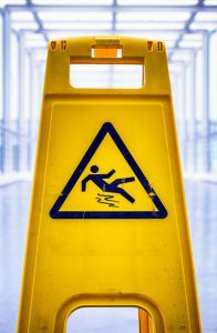 caution wet floor sign at a corridor | How Do Slip and Fall Warning Signs Affect Liability?