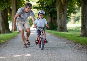 dad helping son ride a bike