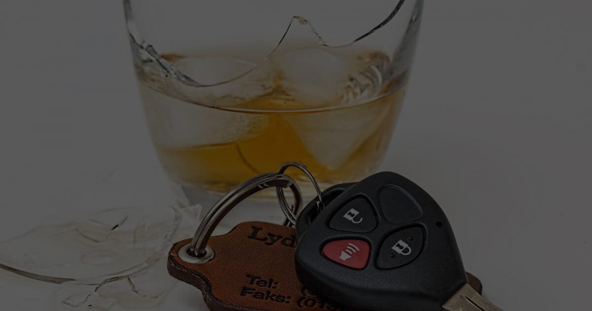 A broken glass with whiskey in it next to car keys