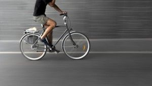 man riding a bike fast on a city street | Bicycle Accident FAQ