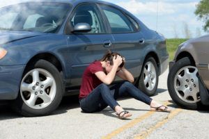 upset woman sitting next to car after a crash | Falcon Car Accident Attorneys
